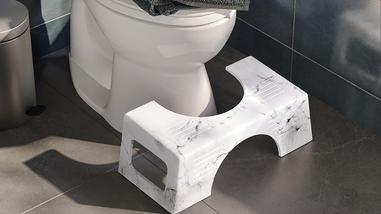 A foot stool in front of a toilet seat