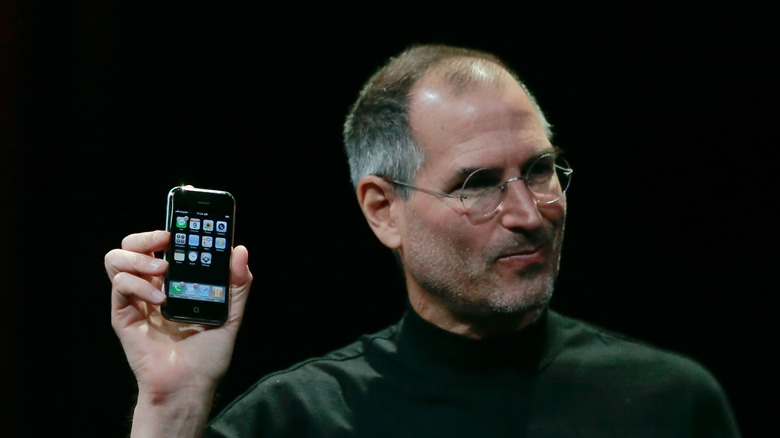 Steve Jobs holding the original Apple iPhone