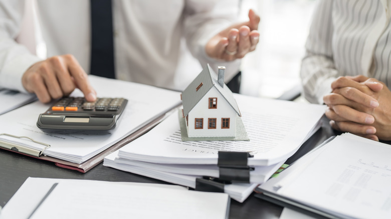 Business people working over documents with model home.