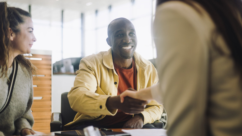 man shaking hands with car salesperson