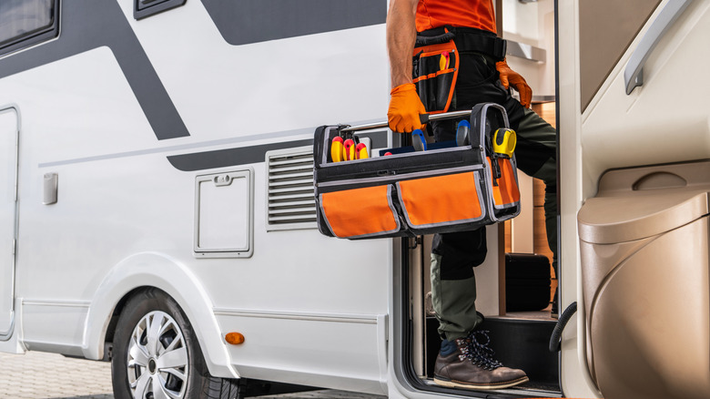 man carrying a toolbox into motorhome