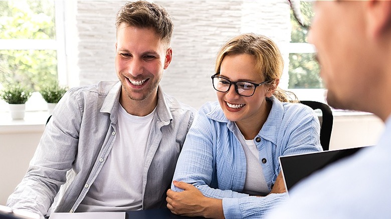 A couple smiles as they sit in a business setting