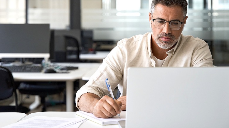 Person looking at laptop, working in empty office