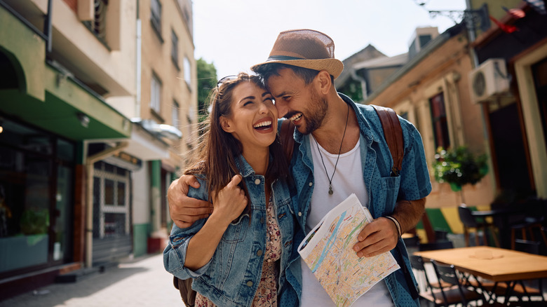 A laughing man and woman hugging and walking down a street