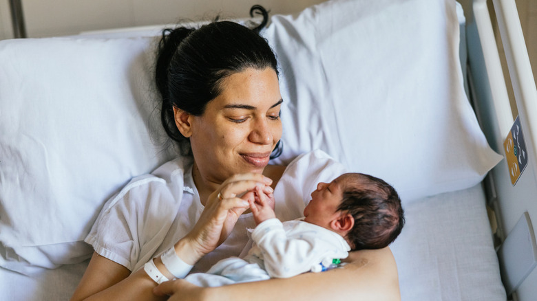 A woman in a hospital bed holding a newborn baby