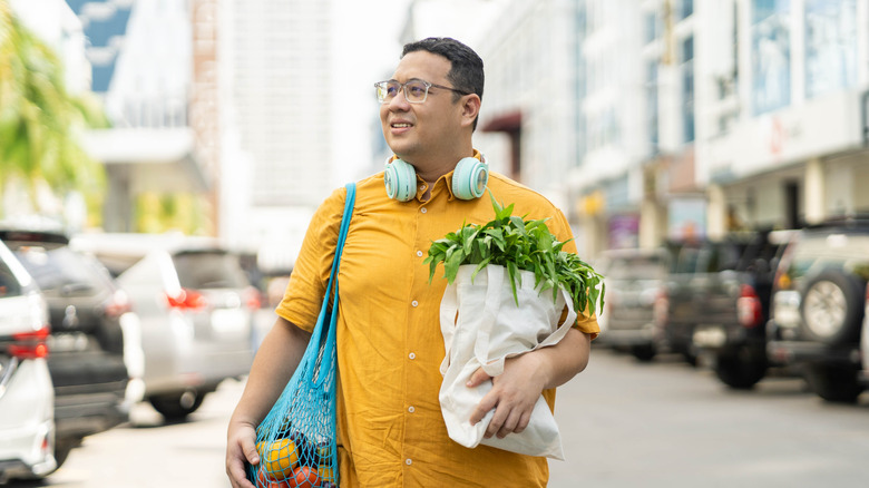 A man walking down the street holding bags of groceries