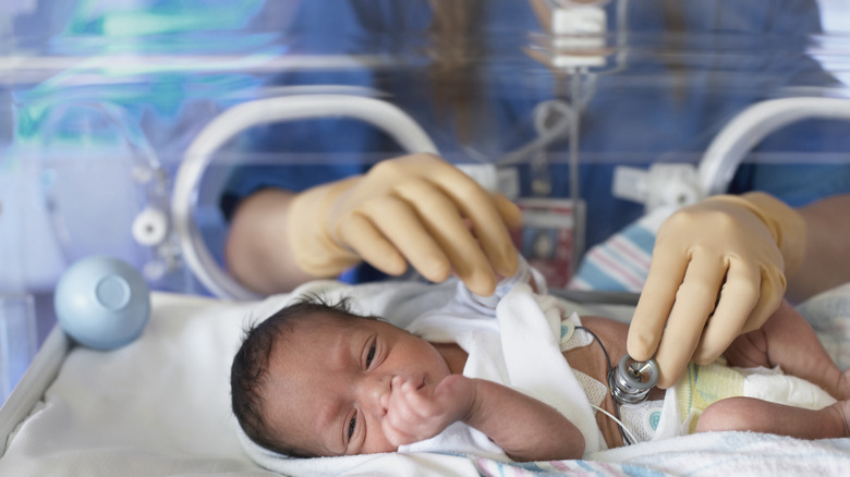 A nurse placing a stethoscope on a newborn baby in a hospital