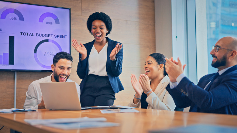 A group of co-workers celebrating during a boardroom meeting