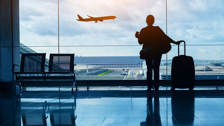 Silhouette of passenger watching aircraft taking of