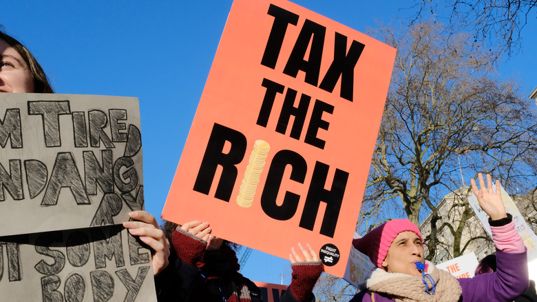 Protestors holding sign saying "tax the rich"