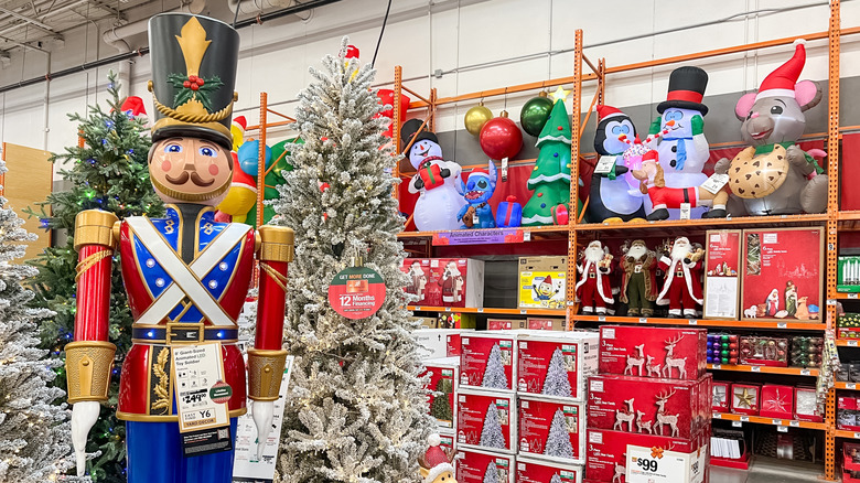 A festive aisle of Christmas decorations for sale in a warehouse store, anchored by a giant nutcracker statue.