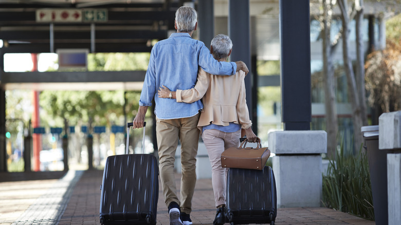 Older couple walking with luggage