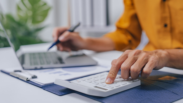 Person looking over paperwork with calculator