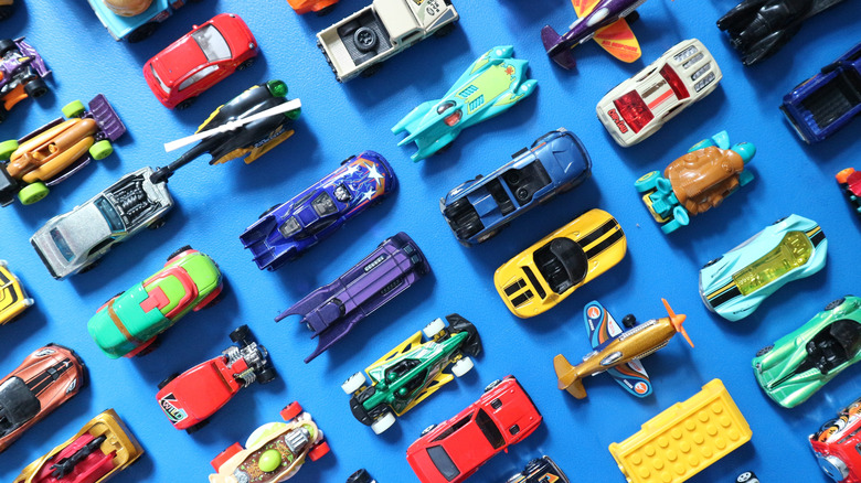 A selection of Hot Wheels cars in different colors and styles on a blue background.