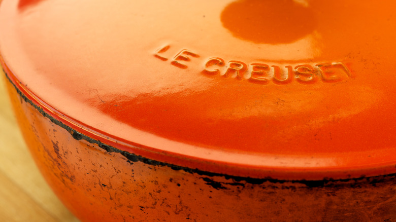 A kitchen-worn, Flame-colored orange Le Creuset dutch oven.