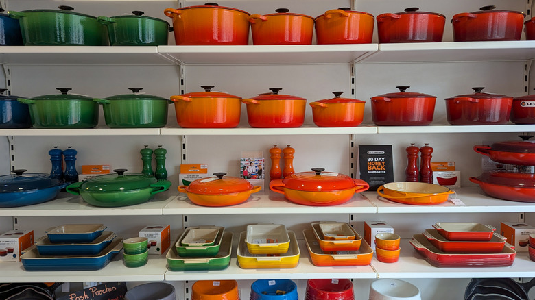 A colorful outlet display of Le Creuset dutch ovens, braisers, and other cookware.