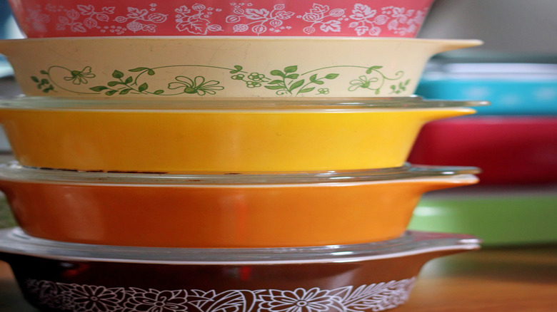 A stack of vintage Pyrex dishes in multiple colors and prints.