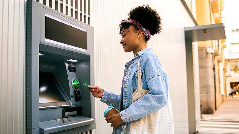 Person holding coffee, using ATM