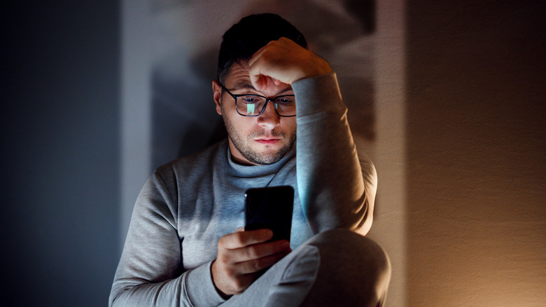Man sitting in dark room on phone