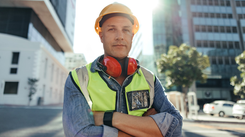 Construction worker stands outside of buildings