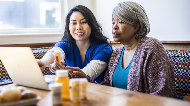 A smiling nurse and an senior woman looking at prescriptions