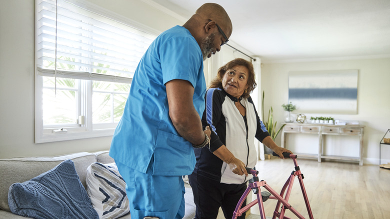 a male nurse helping an elderly woman with a walker