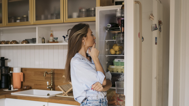 woman staring into refrigerator with open door