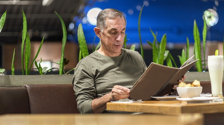 A man reading a menu at restaurant