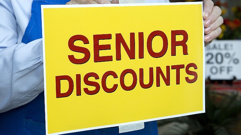 Person placing senior discount sign in store window