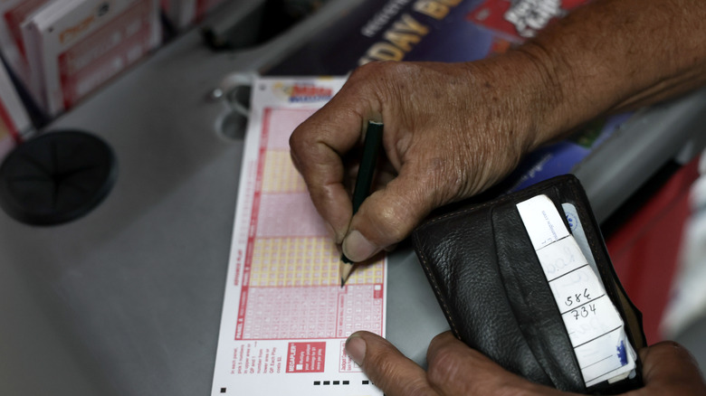 A person fills out his numbers as he plays Mega Millions lottery at the Downtown Miami Souvenirs