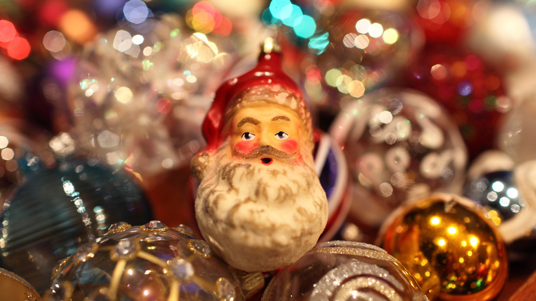 A collection of shiny Christmas ornaments with one depicting an image of Santa Claus in the center of the image.