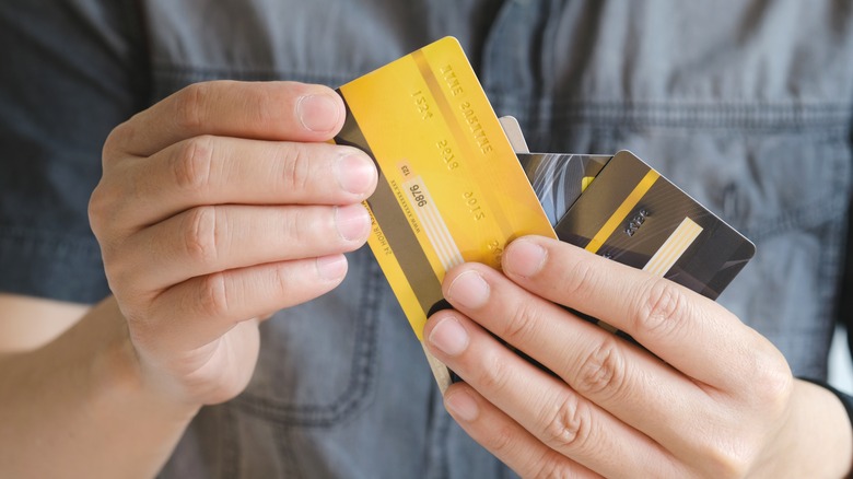 A pair of hands holding multiple credit cards