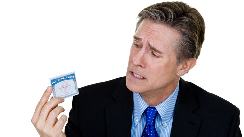 An irritated man holding a social security card