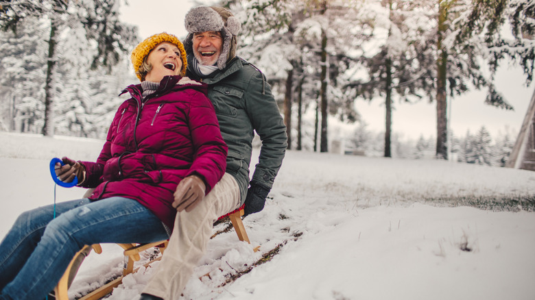 Elderly couple who still enjoy sledding as when they were kids