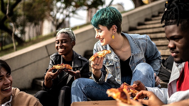 People eating pizza on steps