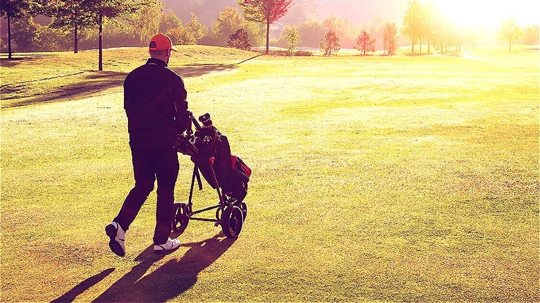 Golfer walking on sunlit fairway