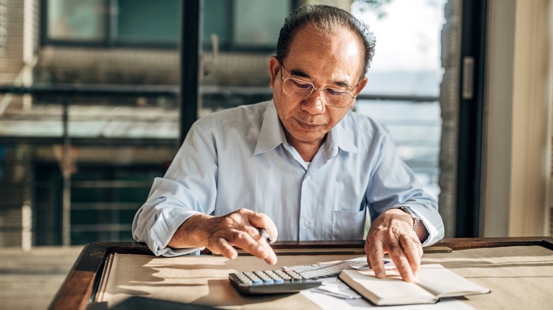 Senior using calculator for accounting