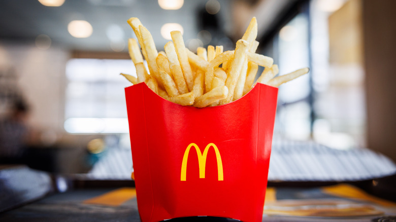 A cheery red box of McDonald's french fries in a brightly lit restaurant.