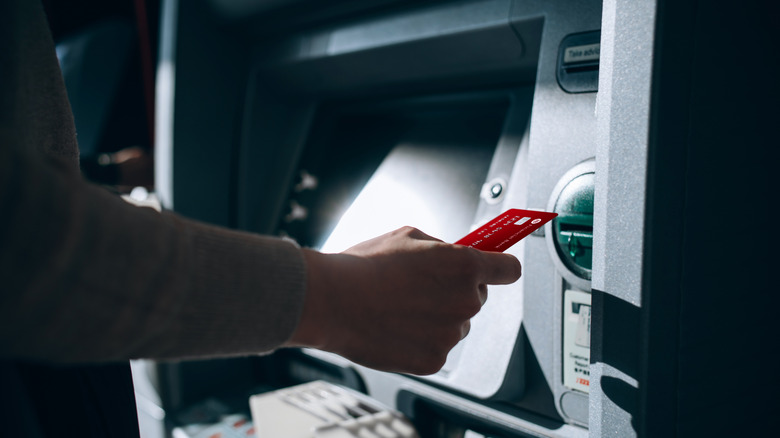 A person inserting a debit card into an ATM machine.