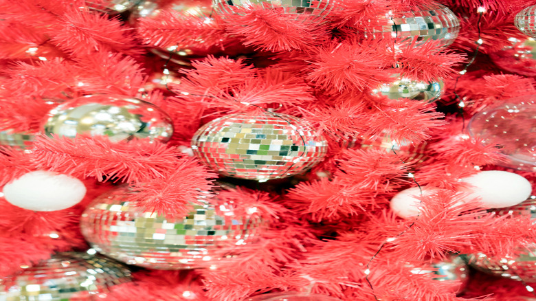 A pink Christmas tree decorated with silver disco balls.