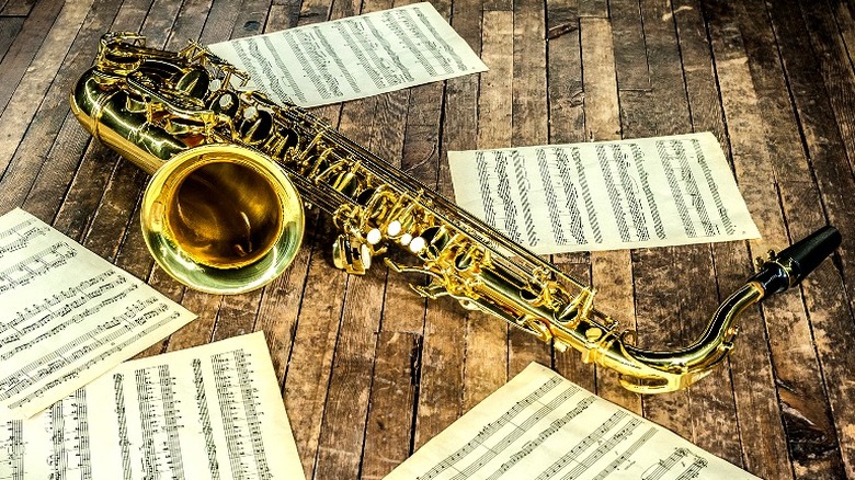 A saxophone lying in a wood panelled floor with sheet music