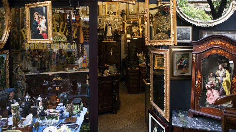 An antique store with old paintings, mirrors, furniture, lamps and statues