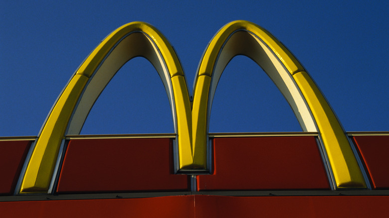 McDonald's famed golden arches, on a red storefront, against a blue sky.