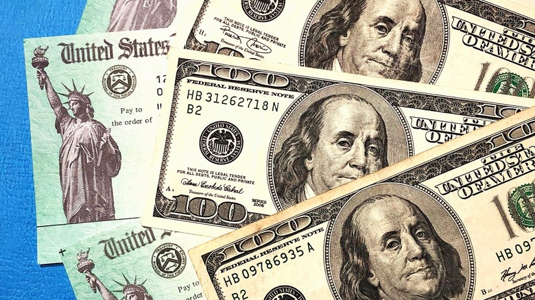 U.S. Treasury check alongside three $100 bills