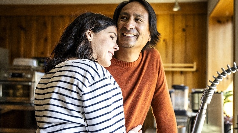 Couple smiling, hugging in kitchen