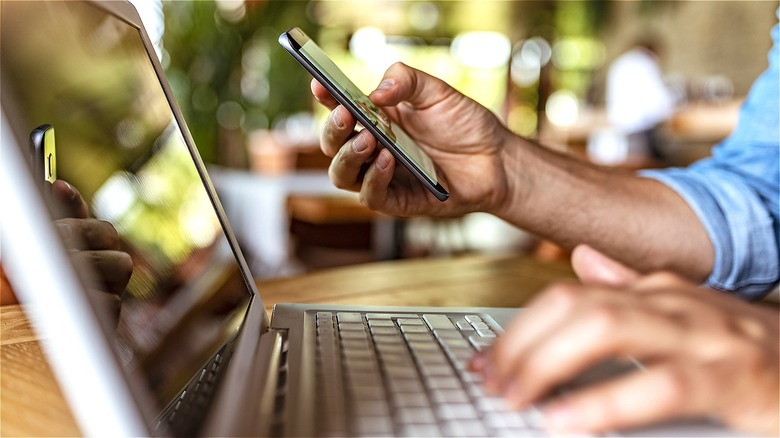 Person using smartphone and laptop