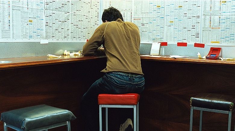 Person at a counter with back to camera and pieces of paper scattered around them