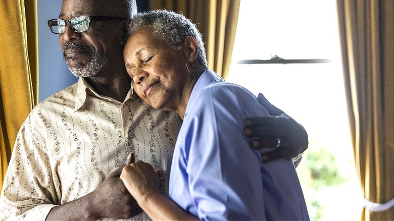 Senior couple embracing by window