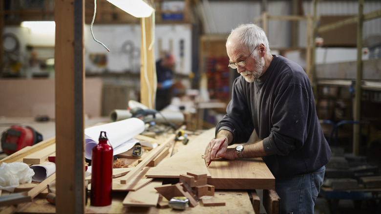 Older man on a wooden carpenter work table