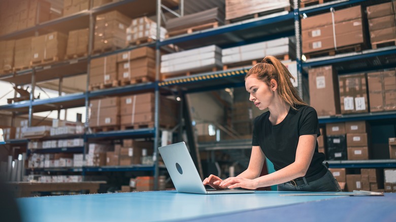 Person using laptop in warehouse